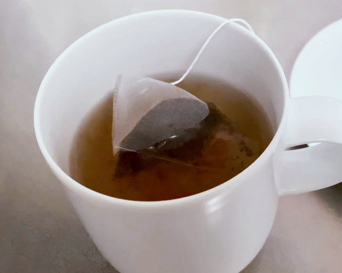 熱湯が入ったマグカップへティーバッグを入れる